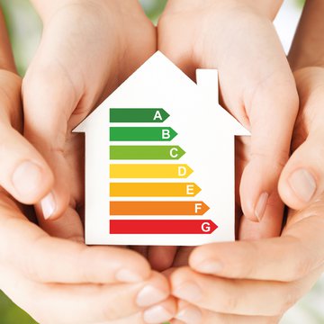 This graphic shows two pairs of hand cradling a model of a house with colour symbols showing various energy ratings.